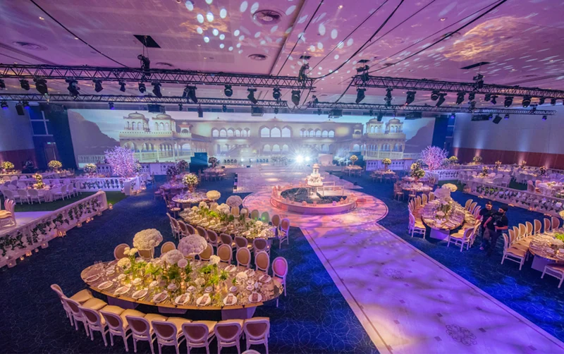 Wedding reception ballroom with banquet seating, an aisle and a large LED stage backdrop