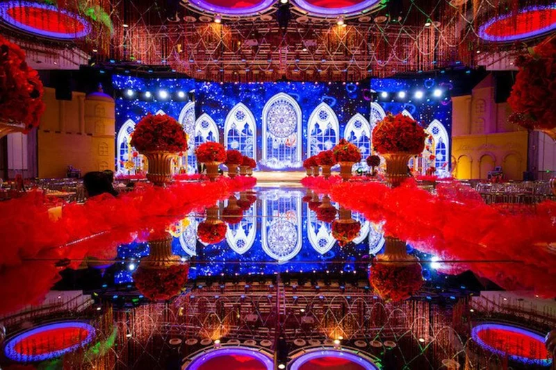 Wedding venue with a reflective aisle, red floral decorations and LED scenic screens
